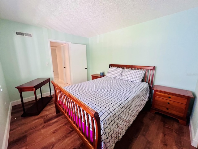 bedroom with a textured ceiling and dark hardwood / wood-style floors