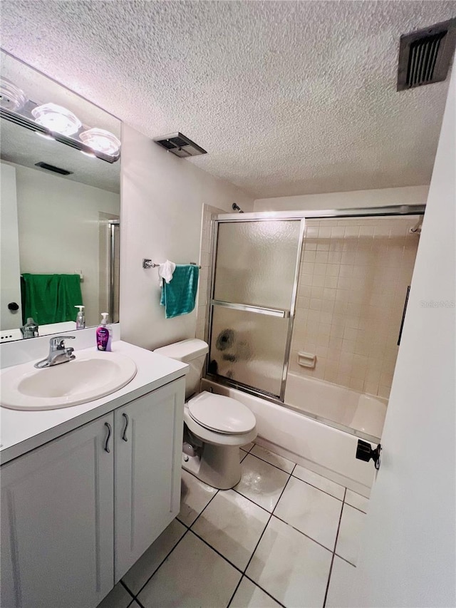 full bathroom featuring tile patterned flooring, enclosed tub / shower combo, a textured ceiling, toilet, and vanity