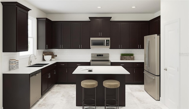 kitchen featuring sink, a kitchen breakfast bar, a kitchen island, backsplash, and appliances with stainless steel finishes