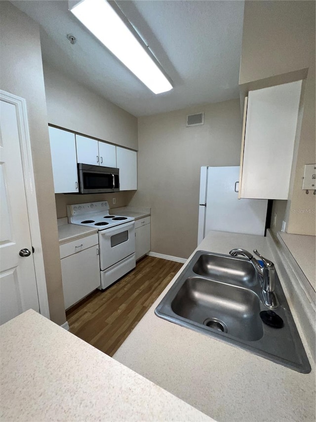 kitchen with white cabinets, dark hardwood / wood-style floors, white appliances, and sink