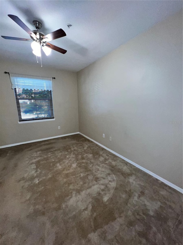 unfurnished room featuring ceiling fan and dark carpet