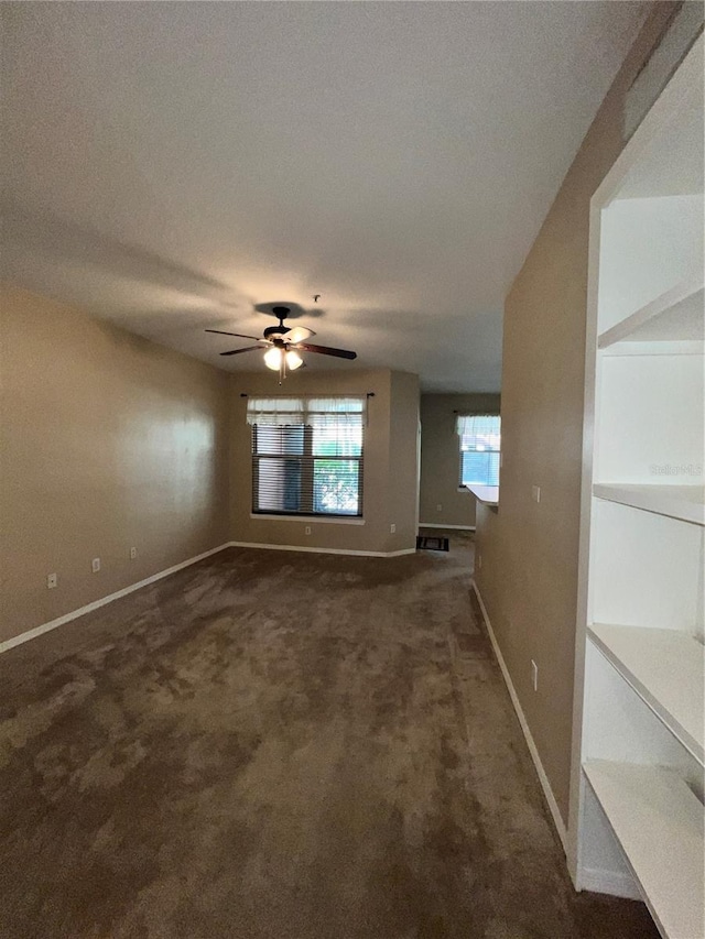 unfurnished room featuring a textured ceiling, dark carpet, and ceiling fan