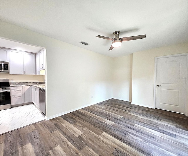 kitchen with light wood-type flooring, stainless steel appliances, white cabinetry, and ceiling fan