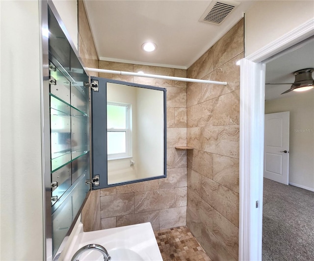 bathroom with ceiling fan, tiled shower, and vanity