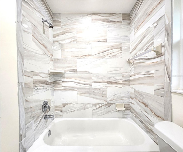 bathroom with tiled shower / bath combo and toilet