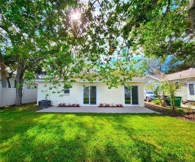 rear view of property featuring a lawn, a patio area, and cooling unit