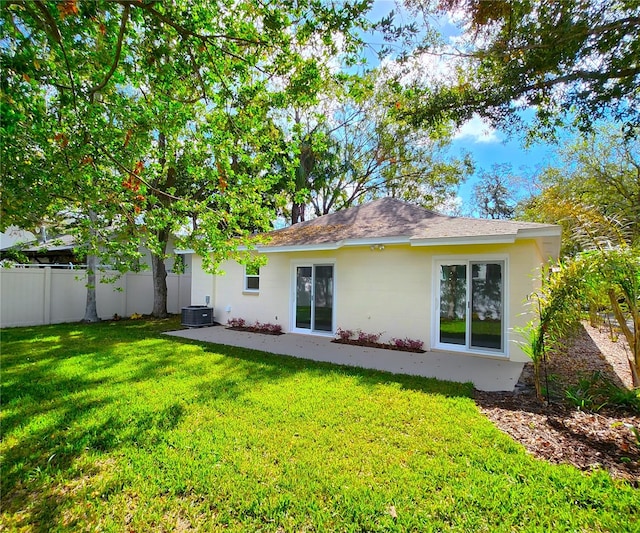 rear view of property featuring central AC unit and a lawn