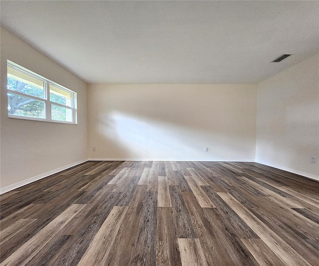 spare room featuring dark wood-type flooring and a textured ceiling