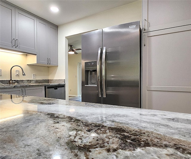 kitchen featuring gray cabinetry, ceiling fan, dark stone counters, and appliances with stainless steel finishes