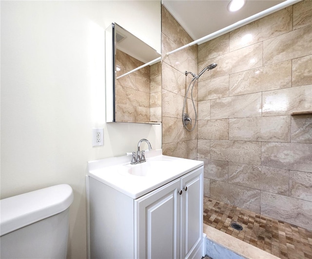 bathroom featuring vanity, toilet, and a tile shower