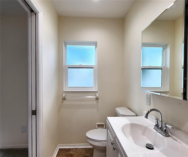 bathroom with toilet, plenty of natural light, vanity, and tile patterned flooring