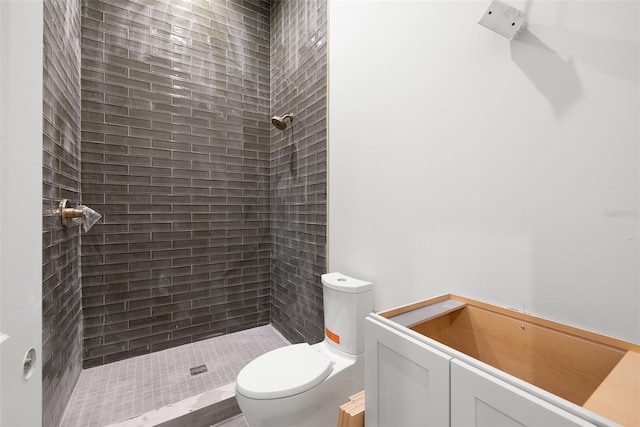 bathroom with toilet, vanity, and a tile shower