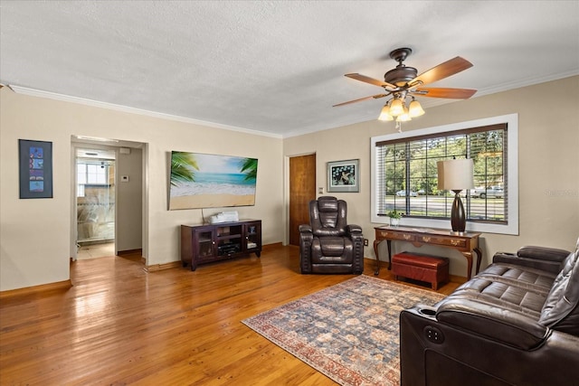 living room featuring ceiling fan, plenty of natural light, wood-type flooring, and a textured ceiling