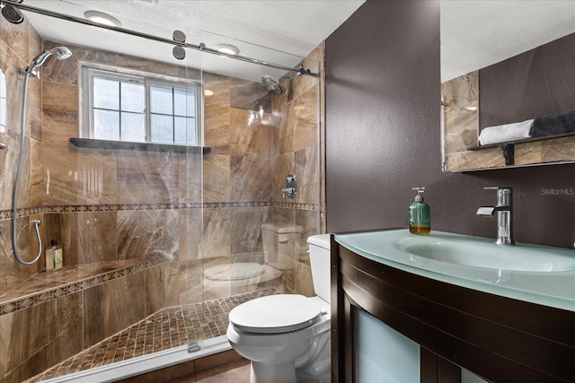 bathroom with a tile shower, vanity, and toilet