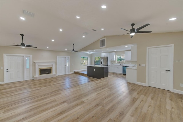 unfurnished living room featuring sink, lofted ceiling, and light wood-type flooring