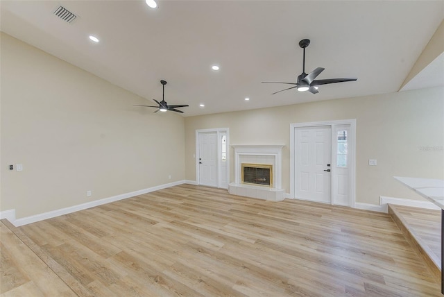 unfurnished living room featuring ceiling fan, a tiled fireplace, and light hardwood / wood-style floors