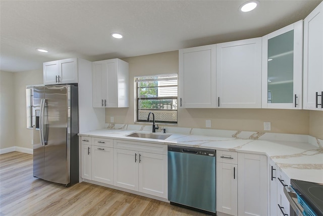 kitchen featuring white cabinets, sink, light hardwood / wood-style floors, stainless steel appliances, and light stone counters