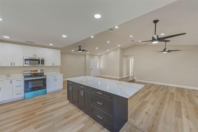 kitchen featuring white cabinetry, a kitchen island, vaulted ceiling, light hardwood / wood-style floors, and stainless steel appliances