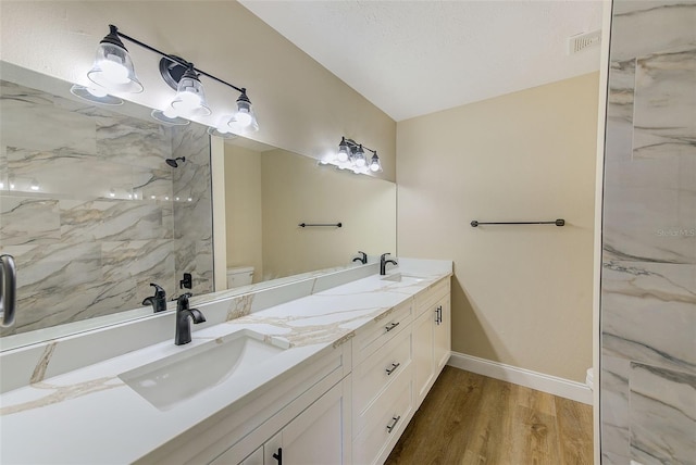 bathroom featuring vanity, toilet, hardwood / wood-style flooring, and a tile shower