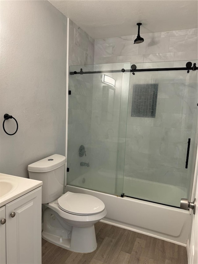 full bathroom featuring hardwood / wood-style floors, vanity, toilet, and shower / bath combination with glass door