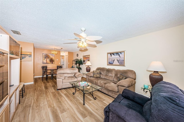 living room featuring a textured ceiling, light hardwood / wood-style flooring, and ceiling fan