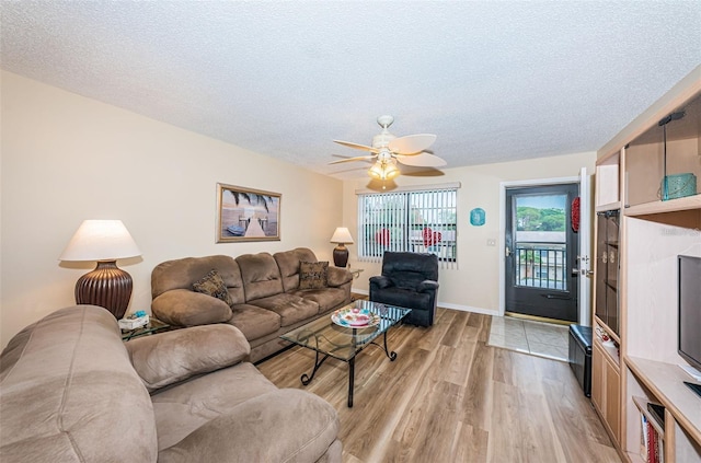 living room featuring a textured ceiling, light wood-type flooring, and ceiling fan