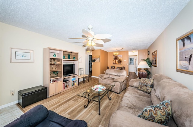 living room with ceiling fan, a textured ceiling, and light wood-type flooring