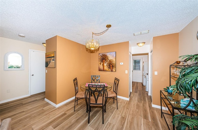 dining area featuring light hardwood / wood-style floors and a textured ceiling