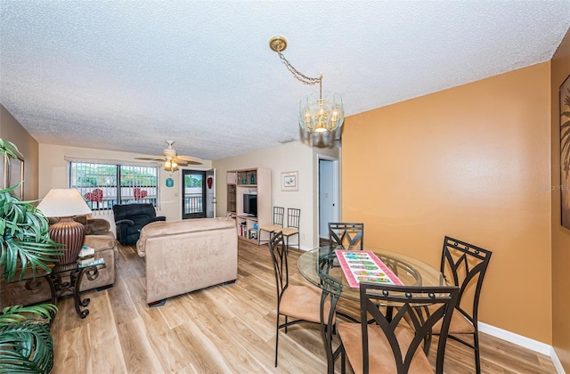 dining area featuring a textured ceiling, light hardwood / wood-style flooring, vaulted ceiling, and ceiling fan with notable chandelier