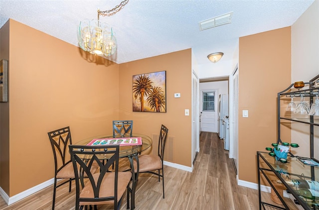 dining area featuring a chandelier, hardwood / wood-style floors, and a textured ceiling