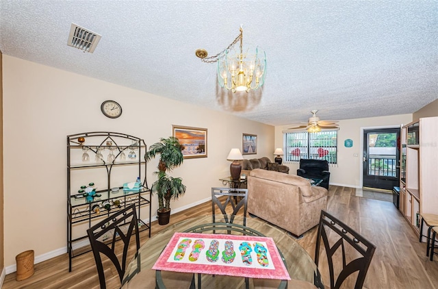 living room with hardwood / wood-style floors, ceiling fan with notable chandelier, and a textured ceiling