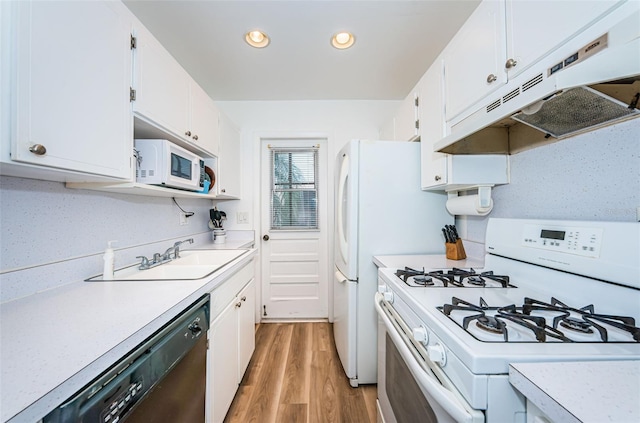 kitchen with white cabinetry, sink, backsplash, wood-type flooring, and white appliances