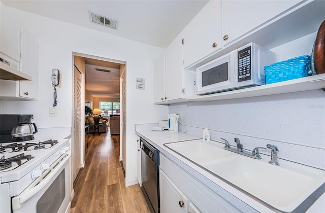 kitchen with white cabinets, hardwood / wood-style floors, white appliances, and sink