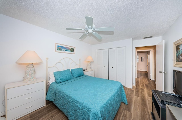 bedroom with ceiling fan, a closet, dark wood-type flooring, and a textured ceiling