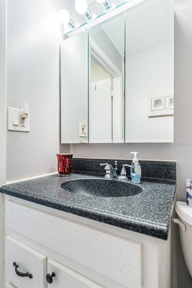 bathroom featuring a textured ceiling, vanity, and toilet