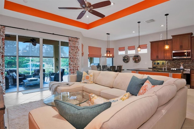 tiled living room with sink and ceiling fan with notable chandelier