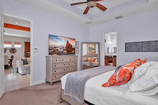 bedroom featuring ceiling fan, light colored carpet, and ensuite bath