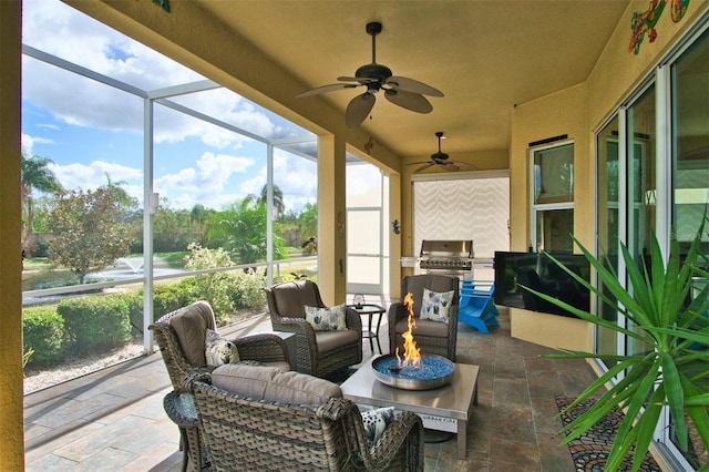 view of patio featuring ceiling fan, a fire pit, grilling area, exterior kitchen, and a lanai