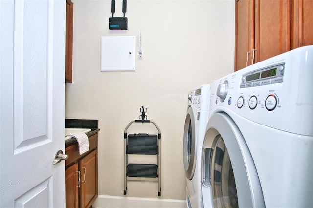 clothes washing area with cabinets and independent washer and dryer