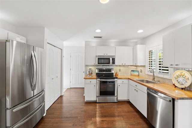 kitchen featuring wood counters, appliances with stainless steel finishes, sink, and white cabinets