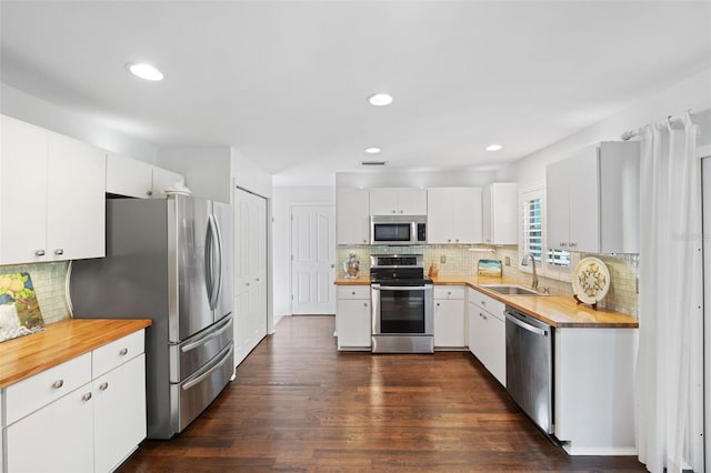 kitchen with sink, dark wood-type flooring, stainless steel appliances, backsplash, and white cabinets