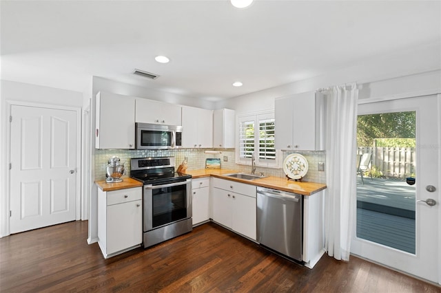 kitchen featuring sink, dark hardwood / wood-style floors, butcher block countertops, white cabinets, and appliances with stainless steel finishes