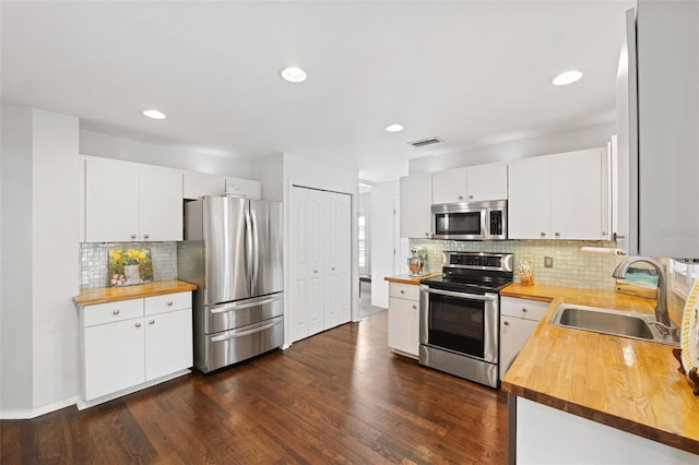 kitchen with white cabinets, appliances with stainless steel finishes, dark wood-type flooring, and sink