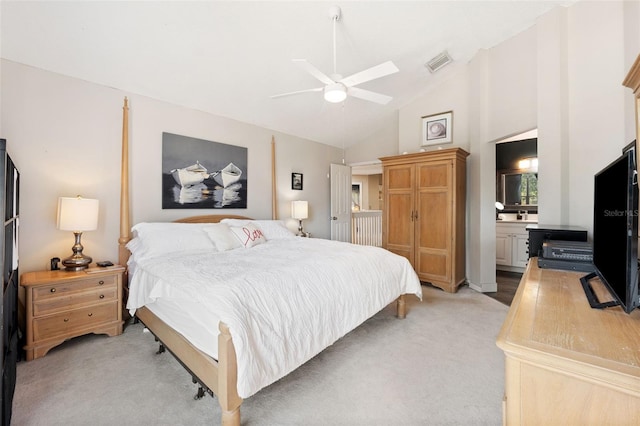 bedroom featuring ceiling fan, light carpet, high vaulted ceiling, and ensuite bath