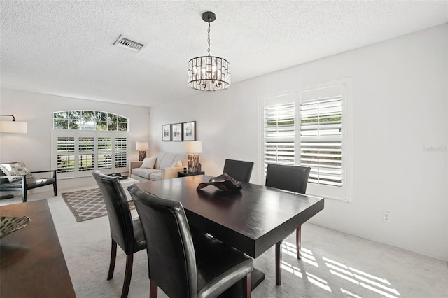 carpeted dining room with a textured ceiling and a notable chandelier