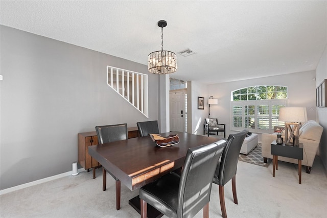 carpeted dining room featuring a textured ceiling and a notable chandelier