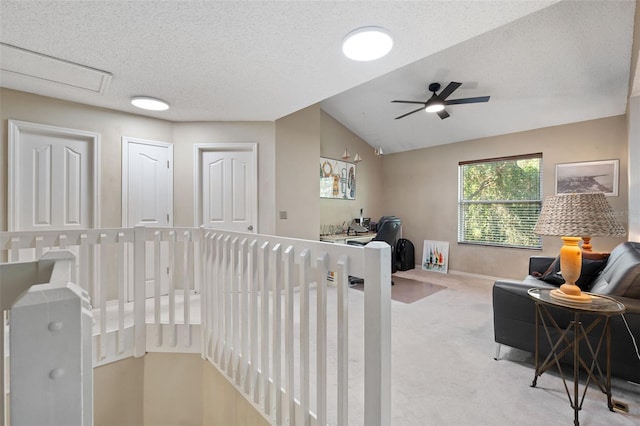 hall with a textured ceiling, light colored carpet, and vaulted ceiling