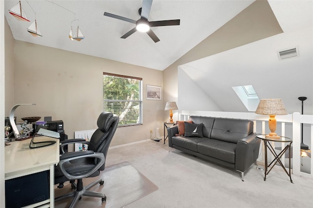 office space featuring light carpet, vaulted ceiling with skylight, and ceiling fan