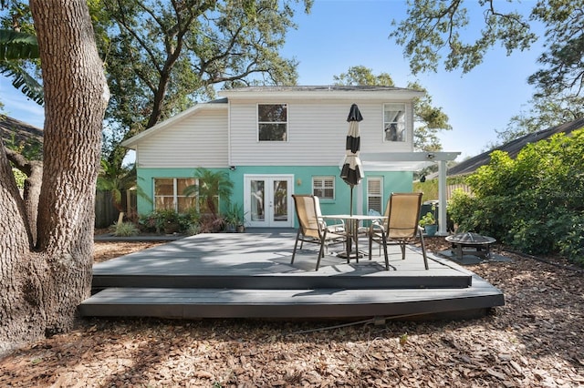 back of property with a wooden deck, french doors, and an outdoor fire pit