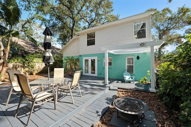 back of property with a wooden deck, french doors, and a fire pit